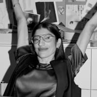 A black and white photo of a person wearing glasses with arms raised, appearing joyful or celebratory